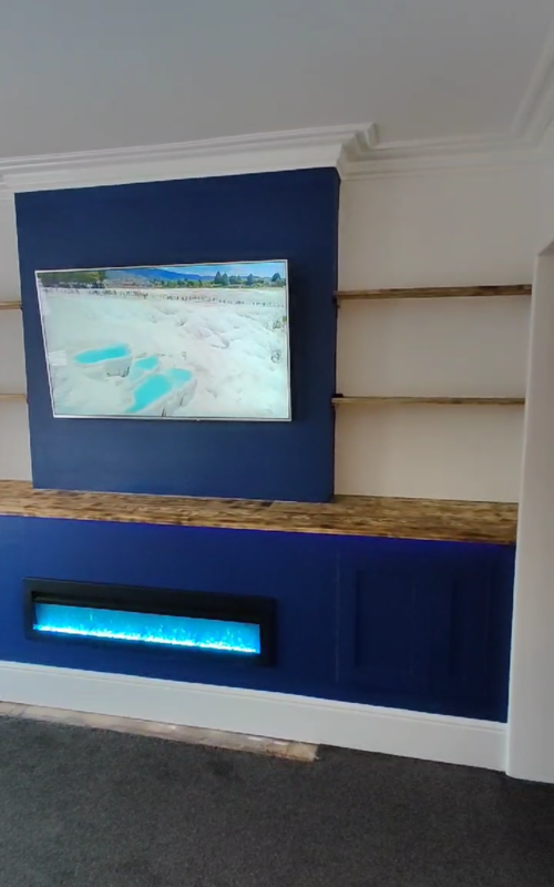 Blue media wall including units, shelves and fireplace.