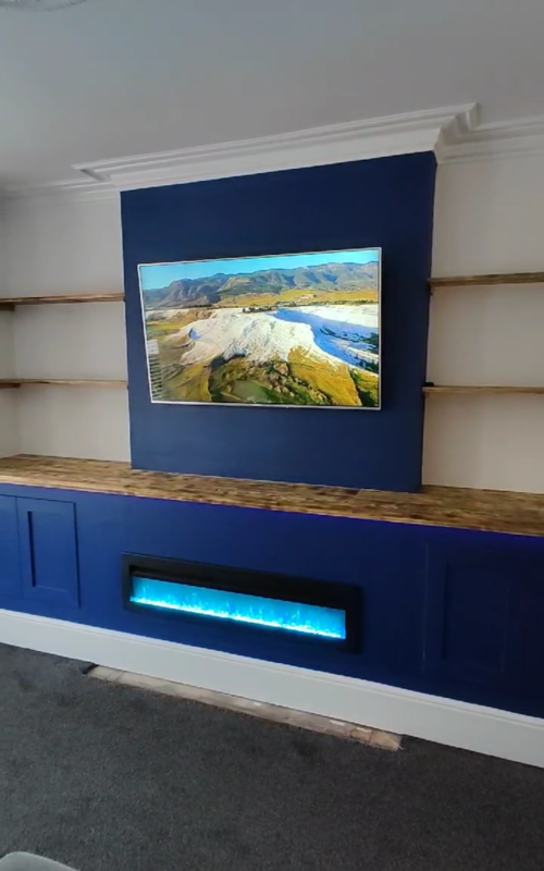 Blue media wall including shelves, units and fireplace.